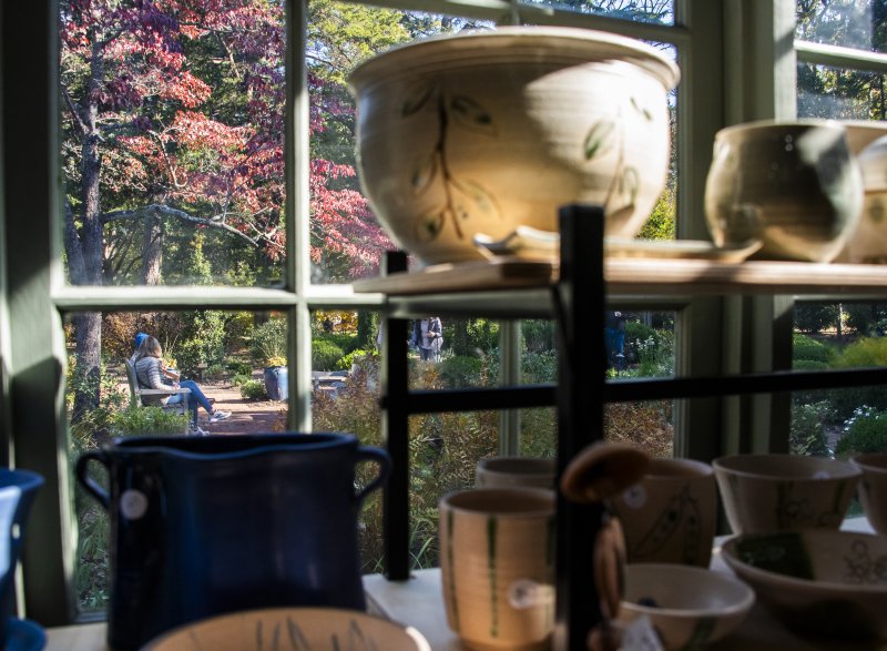 Shoppers relaxing in the Homestead’s formal garden as seen through the windows in the sun porch.